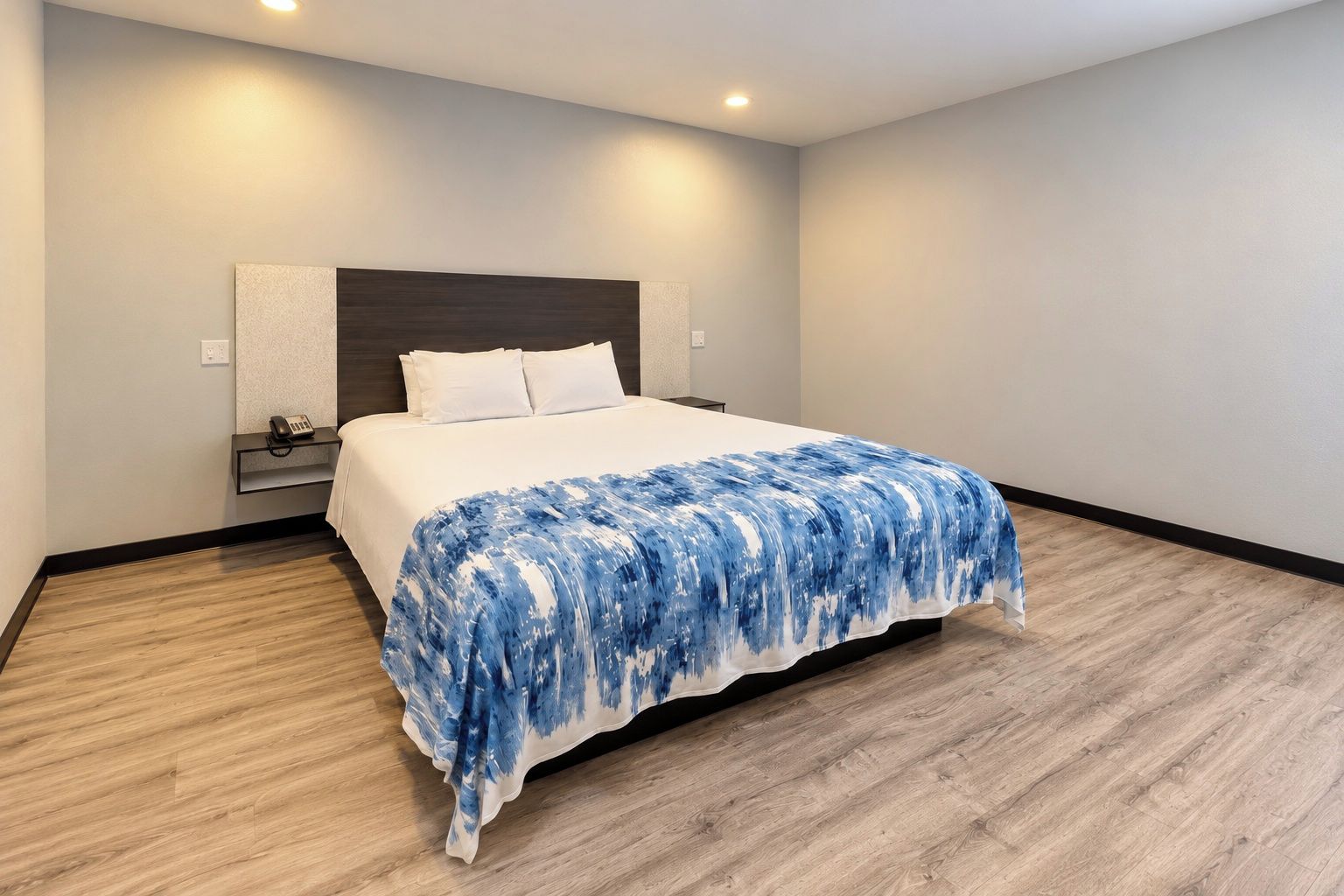 A hotel room with a bed, bedside table, and a phone.