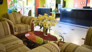 A reception area with a reception desk, a vase of flowers, and a seating area with sofas. - Americas Best Value Inn & Suites Haltom City Ft. Worth (Haltom City)