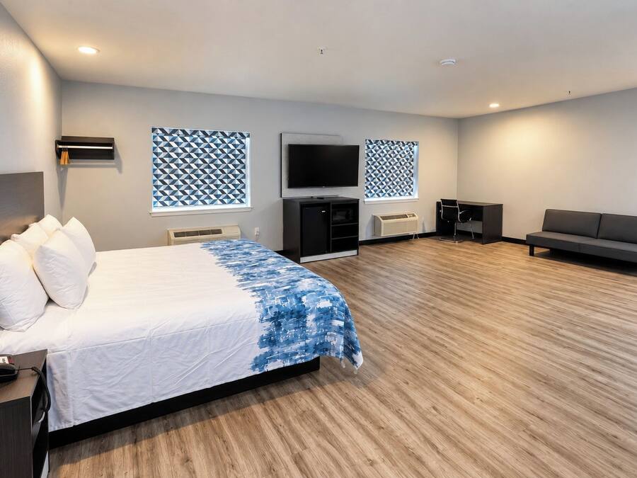 A hotel room with a bed, a sofa, a TV, and a desk with a phone.