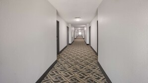 A long, narrow hotel corridor with patterned carpet and white walls. - Quality Inn & Suites Clayton, NM (Clayton)