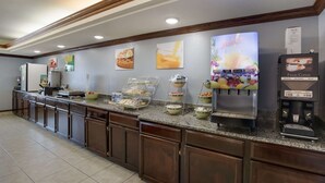 A hotel breakfast area with a self-serve station, including a juice dispenser and a coffee maker. - Quality Inn & Suites Clayton, NM (Clayton)