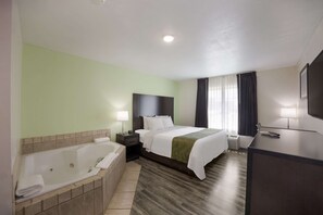 A hotel room with a large bed, a separate bathroom with a bathtub, a desk, and a TV.