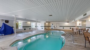 A large indoor pool with a curved design, surrounded by lounge chairs and a table. - Quality Inn & Suites Clayton, NM (Clayton)