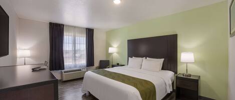 A hotel room with a bed, bedside tables, a desk, and a window with curtains.