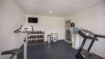 Une salle de sport équipée d’un tapis de course, d’haltères et d’un vélo d’appartement.