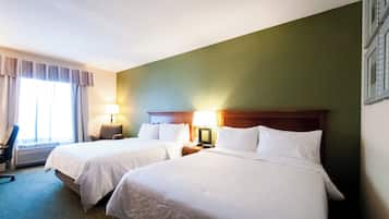 Habitación de hotel con dos camas, una silla, un escritorio y una lámpara.