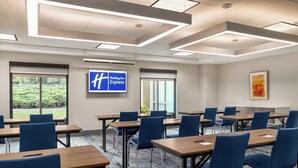 A conference room with tables, chairs, and a large screen displaying the Holiday Inn Express logo.