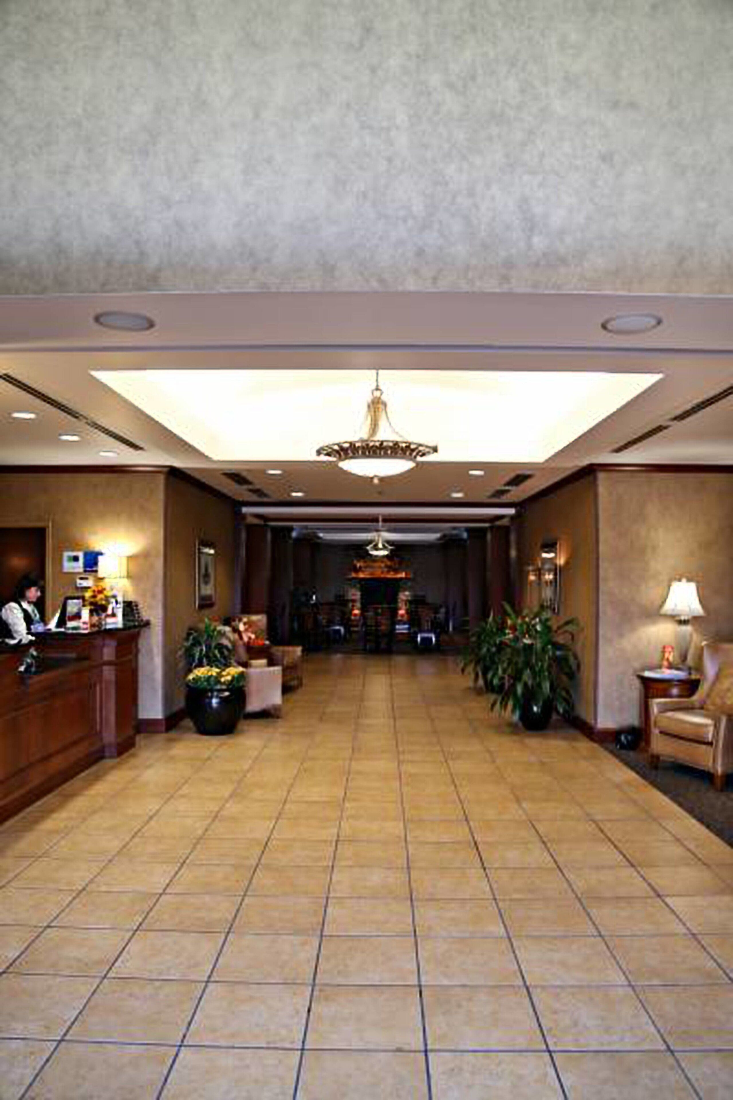 A hotel lobby with a reception desk, seating area, and a chandelier.