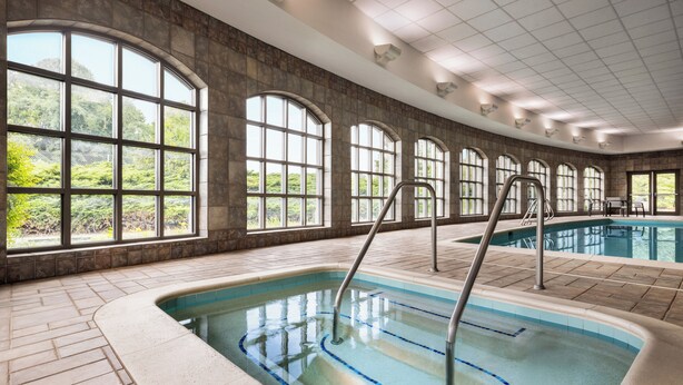An indoor swimming pool with arched windows and a tiled floor.