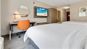 Een hotelkamer met een bed, een bureau met stoel, een televisie en een kledingkast.