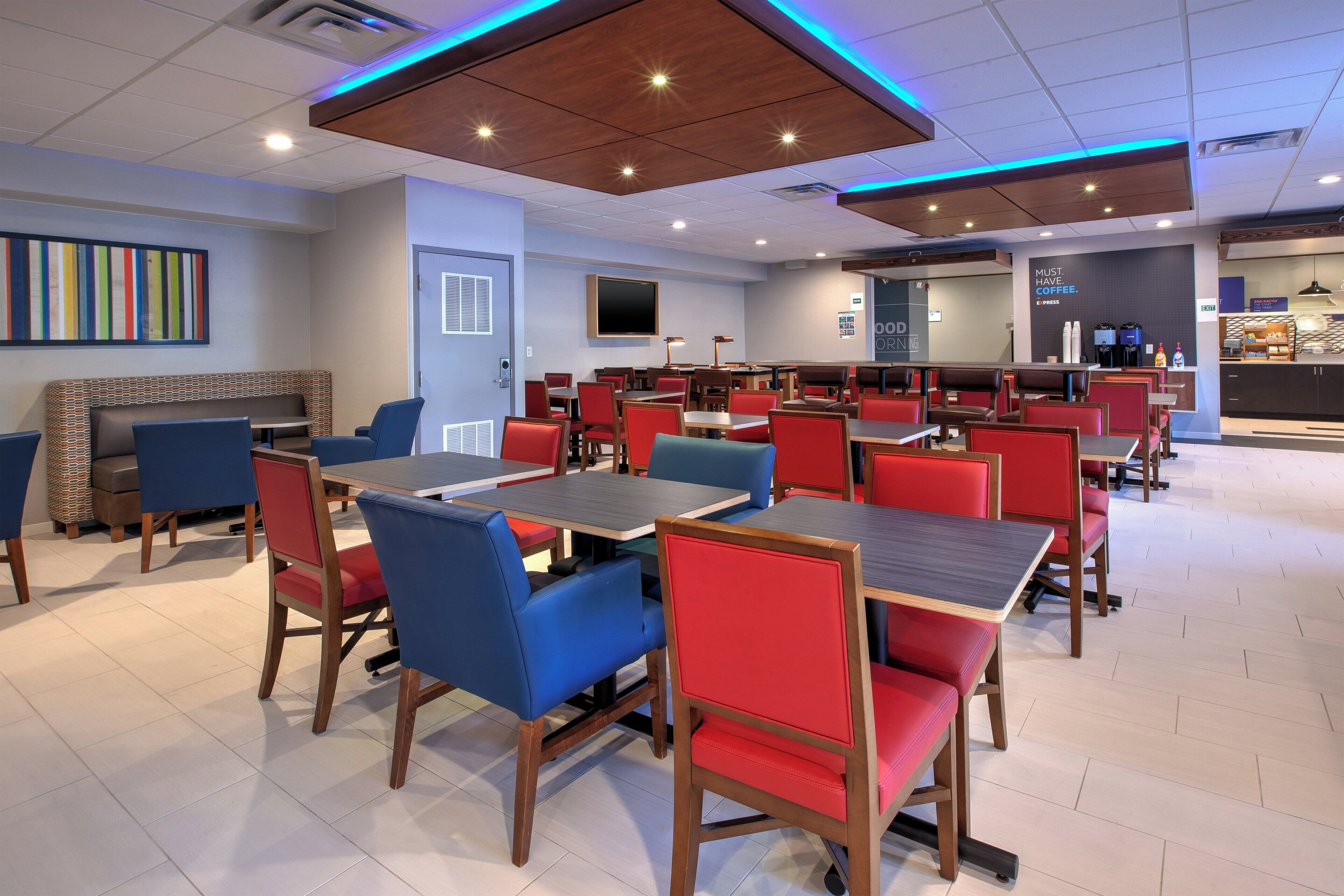 Un ristorante moderno con banconi e tavoli, un bancone e un muro decorato con un'opera d'arte colorata.
