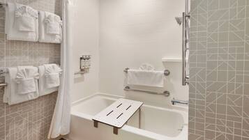 A bathroom with a bathtub, a shower, and a towel rack with multiple towels.