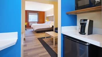 A hotel room with a bed, a desk, a microwave, and a coffee maker.