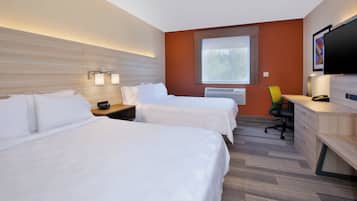 A hotel room with two beds, a desk, a chair, a TV, and a window.