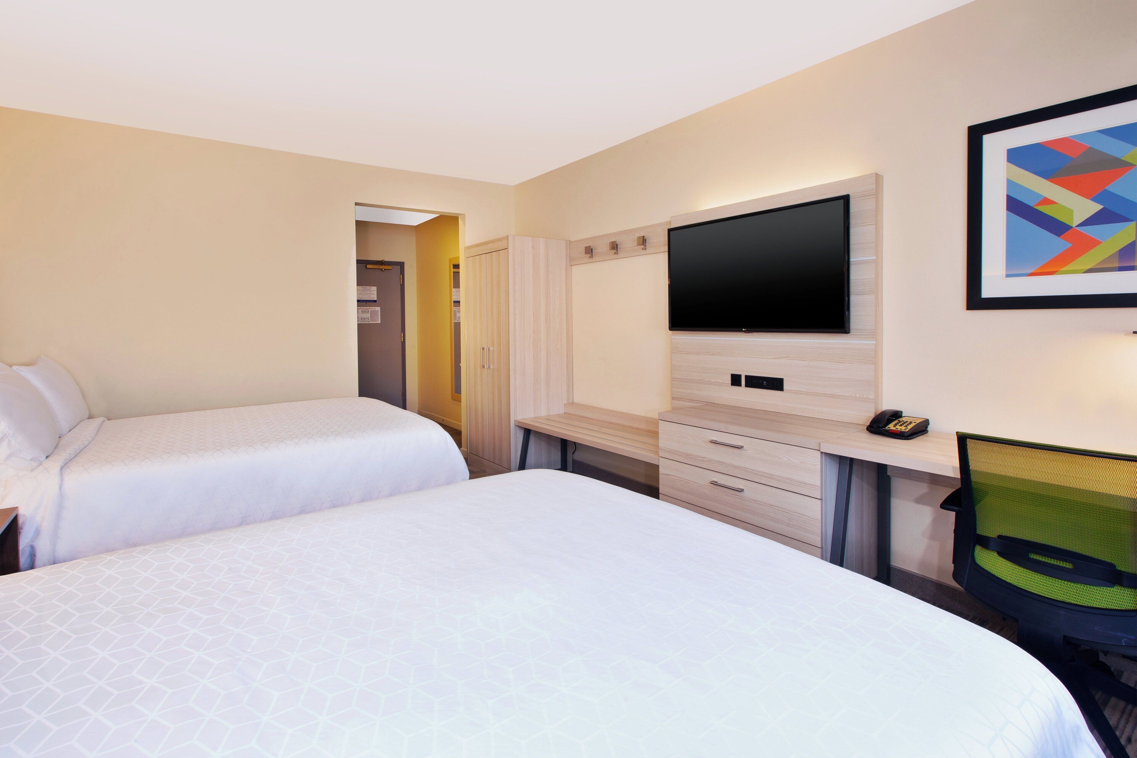 Quarto de hotel com duas camas, televisão, escrivaninha e uma cadeira.