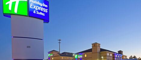 Un hotel Holiday Inn Express & Suites con un letrero llamativo, una fachada bien iluminada y una vista despejada del estacionamiento.