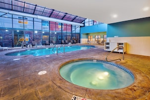Ein Innenpool mit Whirlpool, Liegestühlen und einer Rezeption.
