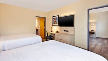A hotel room with two beds, a desk, a flat-screen TV, and a painting on the wall.