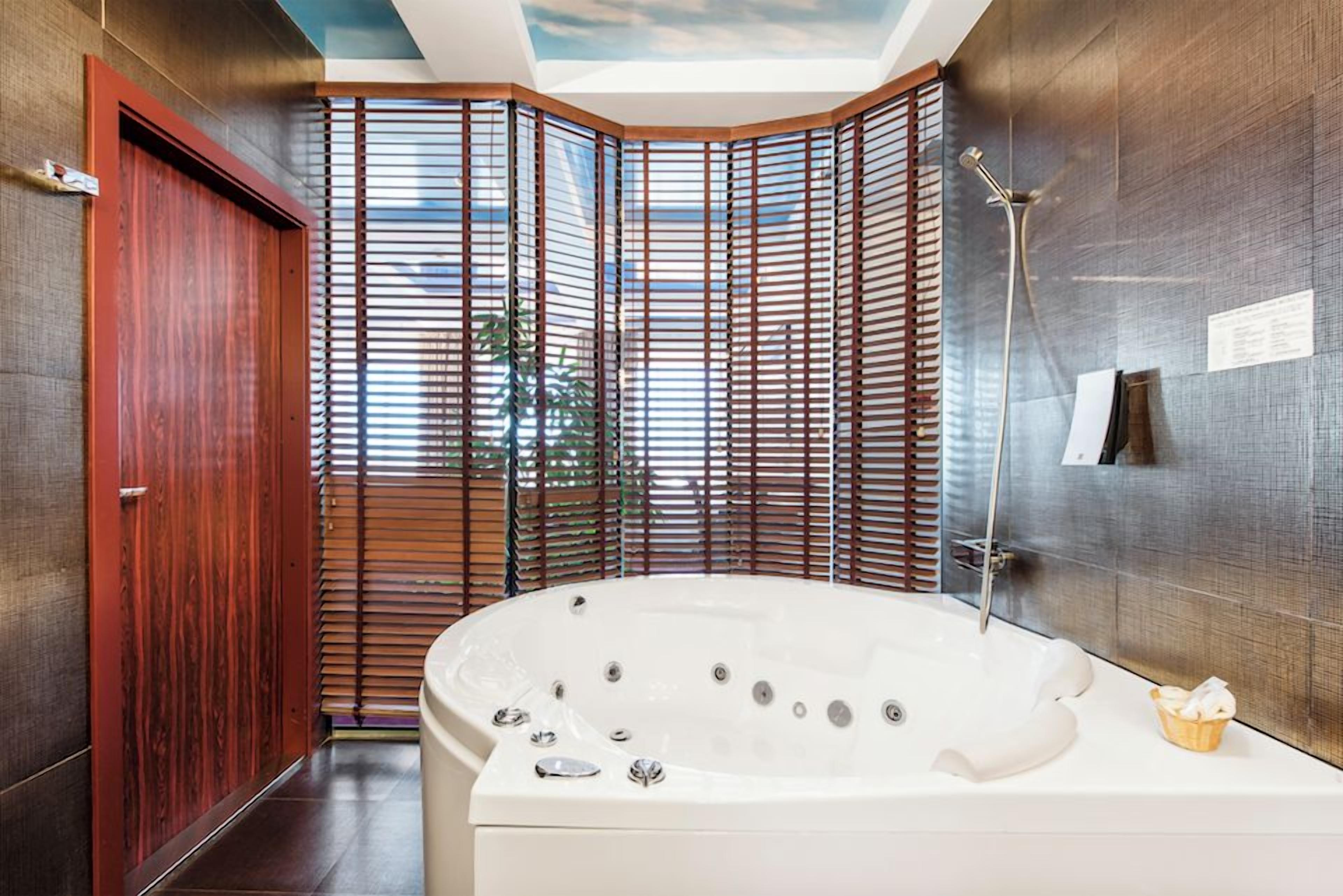 Un baño moderno con una bañera grande, ducha y un separador de madera.