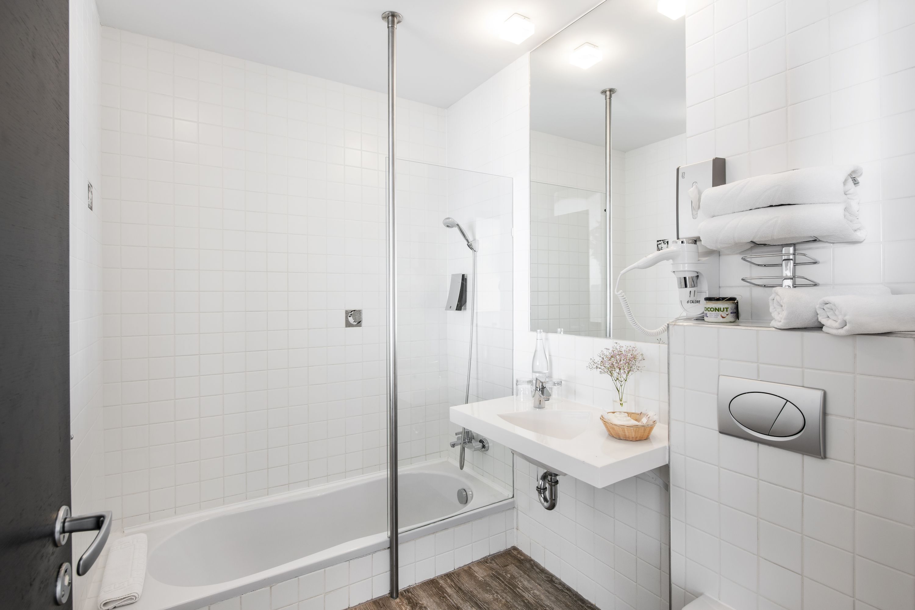 Un baño moderno con ducha envuelta en vidrio, una bañera blanca y un tocador con lavabo y espejo.