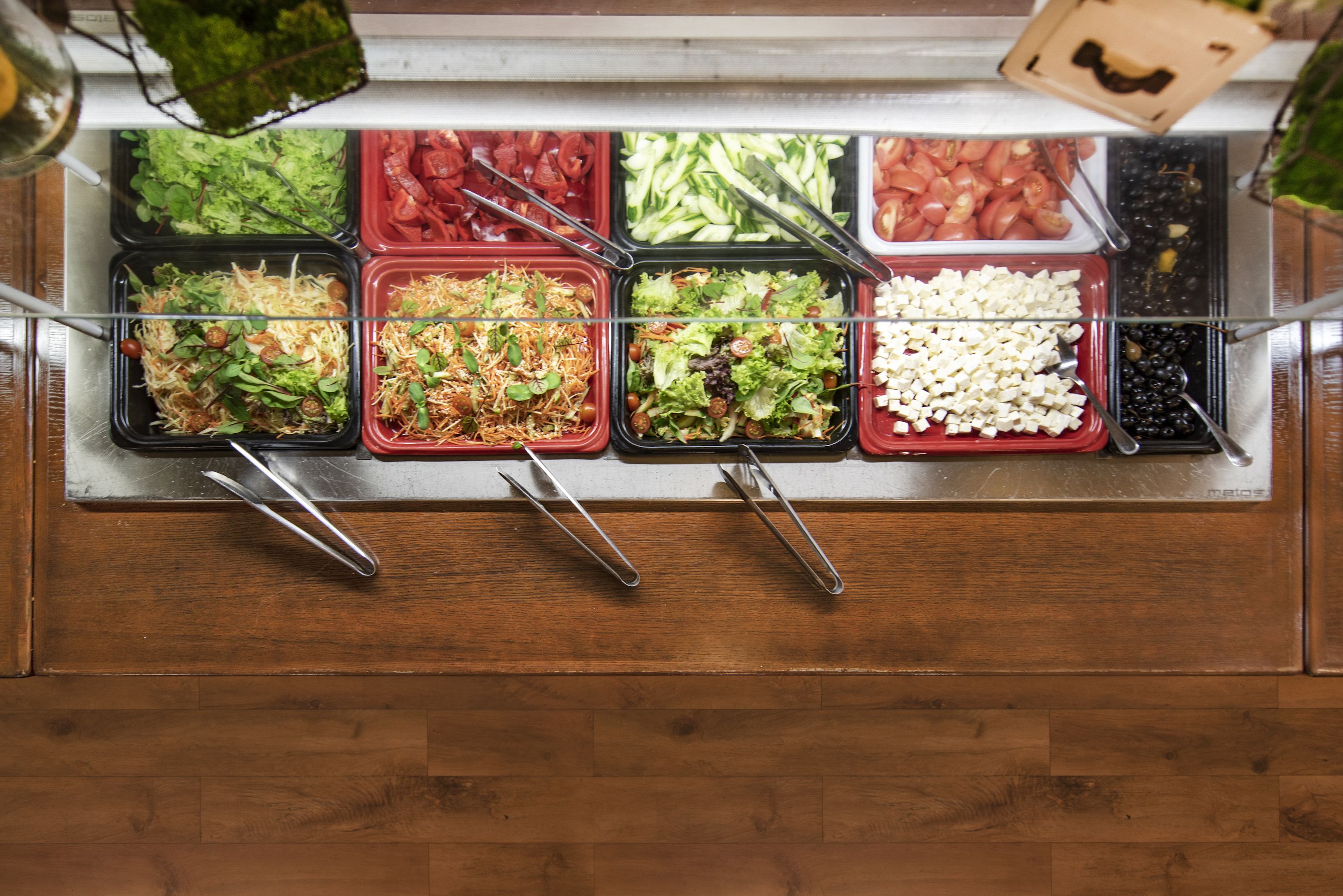 A salad bar with various types of salads and toppings.
