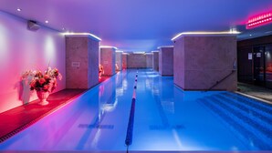 A swimming pool with a central lane divider, surrounded by walls with recessed lighting and a red carpet path. - Amberton Hotel Klaipeda (Klaipeda)