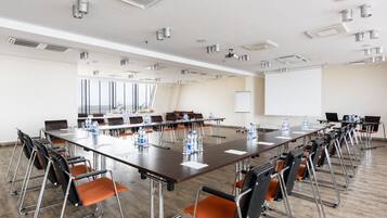 A conference room with a long table, multiple chairs, and a projector screen.