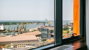 A view of a port with cranes and a ship, buildings, and a body of water. - Amberton Hotel Klaipeda (Klaipeda)
