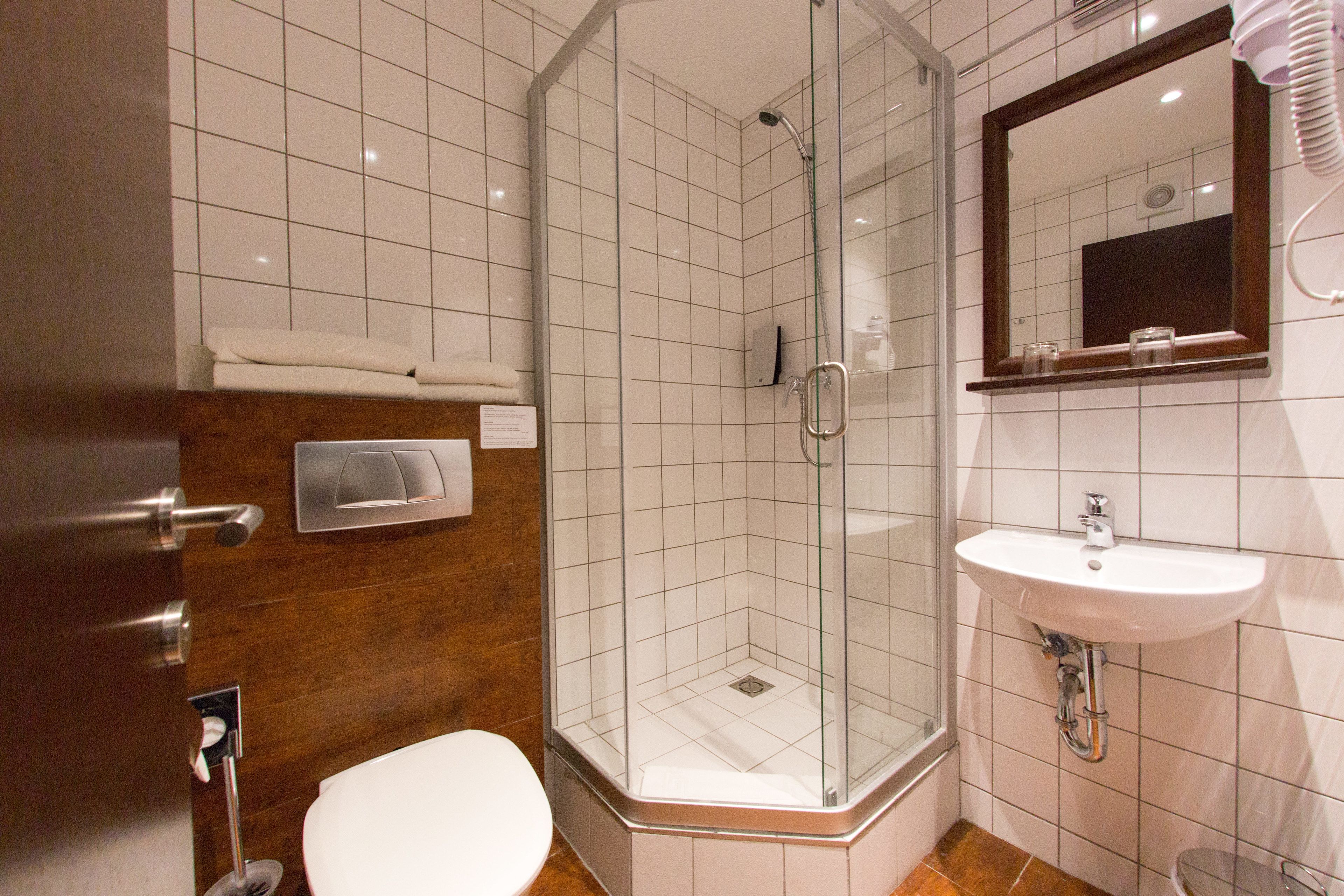 Een badkamer met een douchecabine van glas, een wit wastafeltje en een toilet.