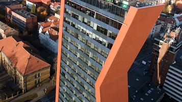 A high-rise building with a modern design, featuring a prominent orange facade and multiple windows.