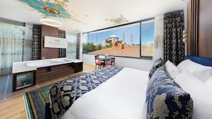 A hotel room with a large bed, a desk, and a view of a mosque. - Seven Hills Hotel - Special Class (Istanbul)