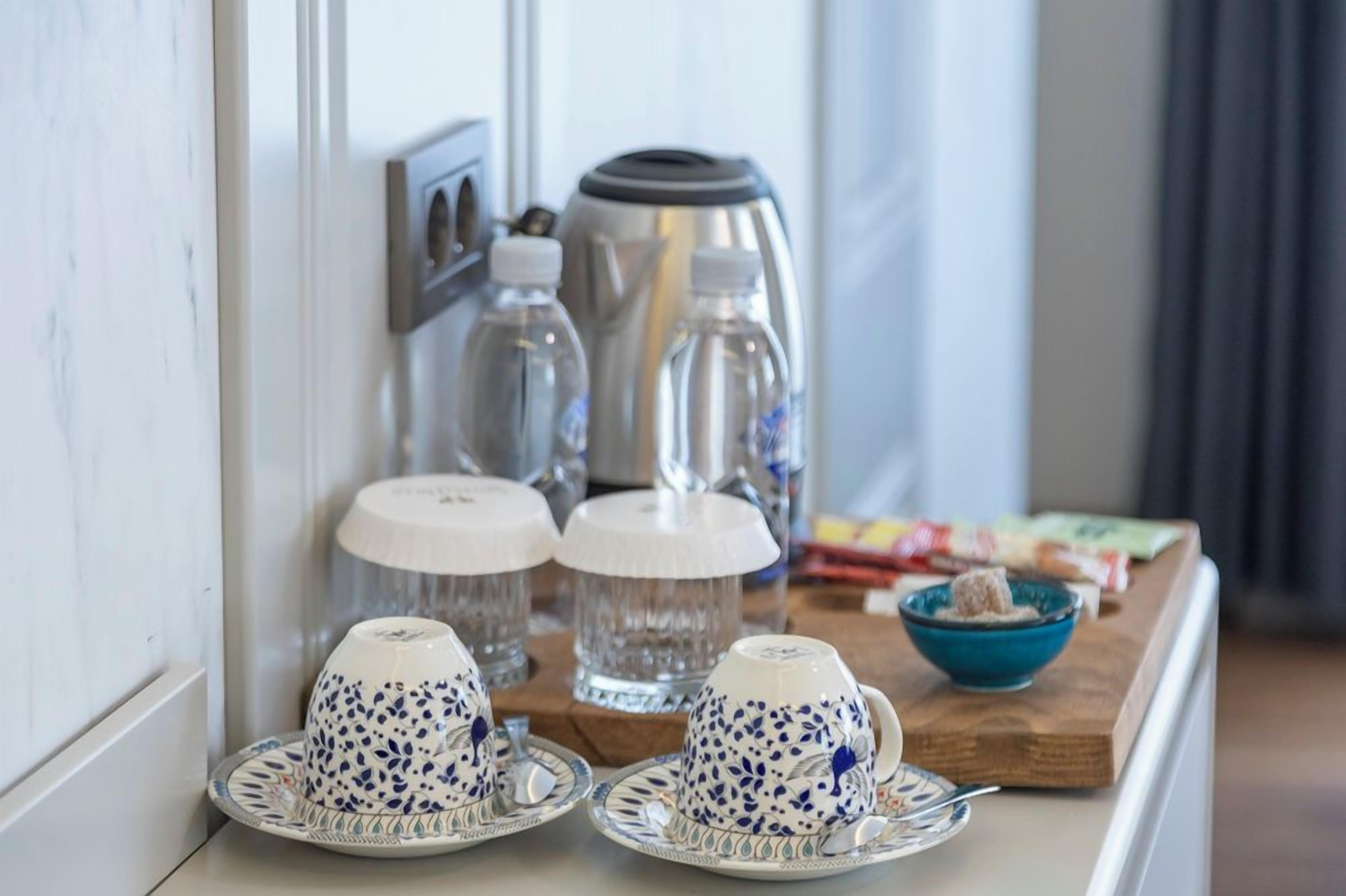A breakfast setup with teapots, water bottles, and a bowl of cereal on a wooden tray.