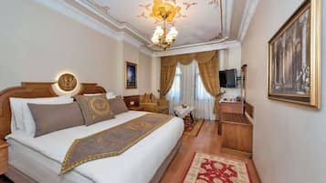 Une chambre d’hôtel avec un grand lit, un lustre, une télévision et un tableau au mur.