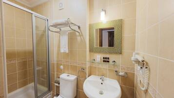 Een badkamer met een douchecabine van glas, toilet, wastafel en spiegel met decoratieve lijst.