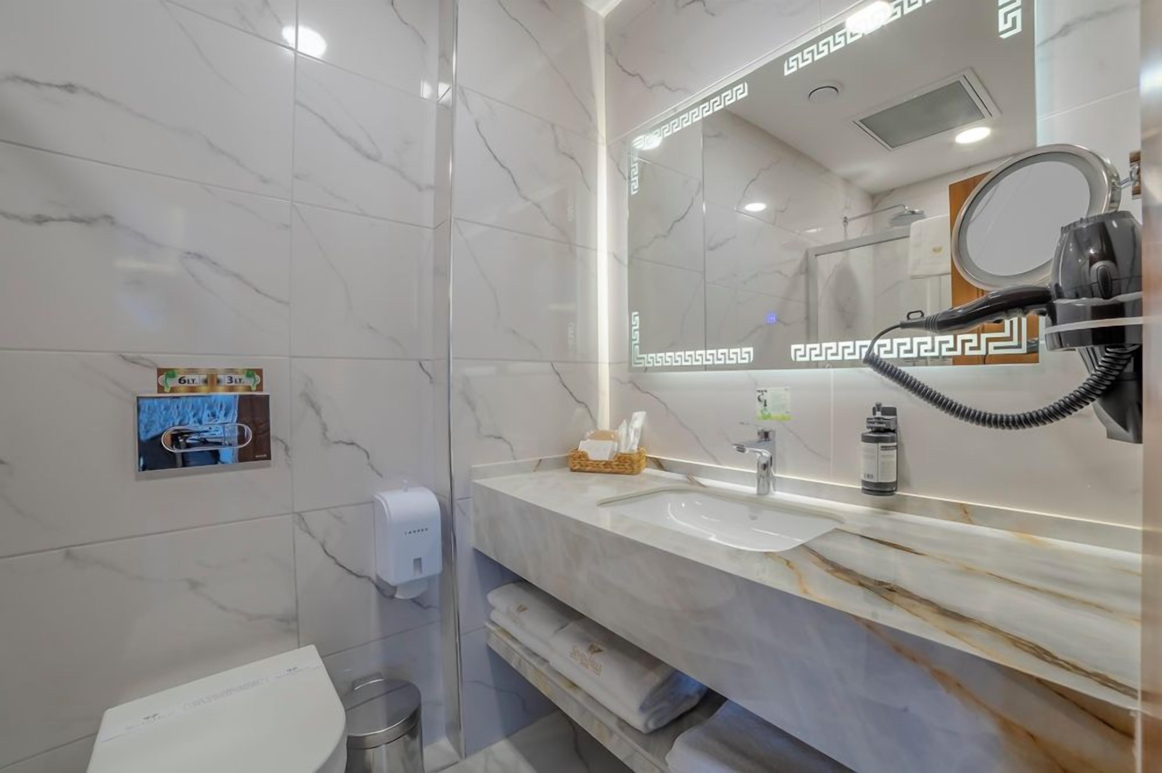 A bathroom with a marble vanity, a mirror, a hairdryer, and a hand dryer.