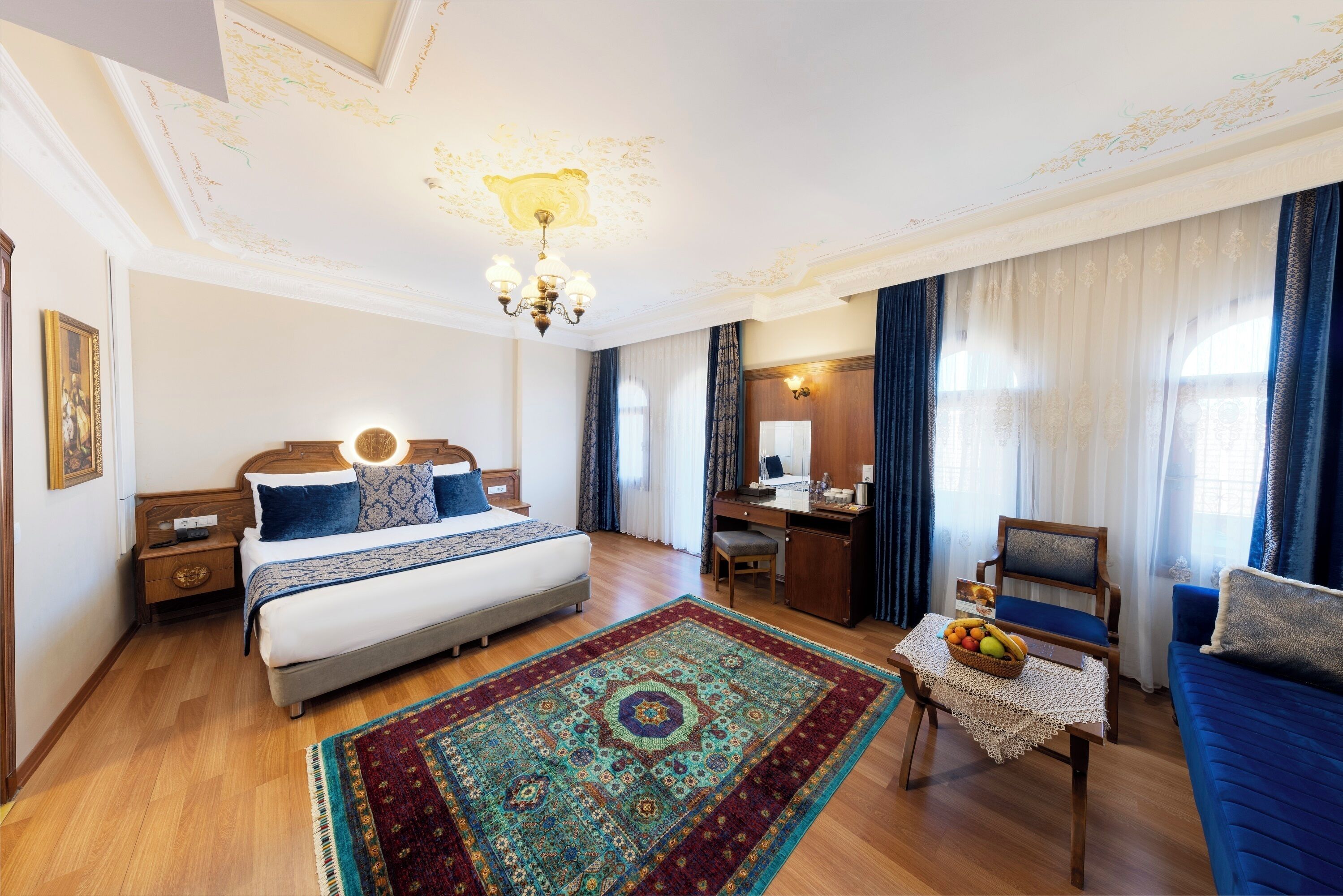 Habitación de hotel elegante con una cama grande, un escritorio, una silla y un sofá.
