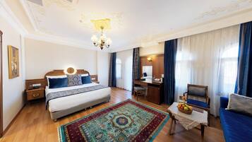 Habitación de hotel elegante con una cama grande, un escritorio, una silla y un sofá.
