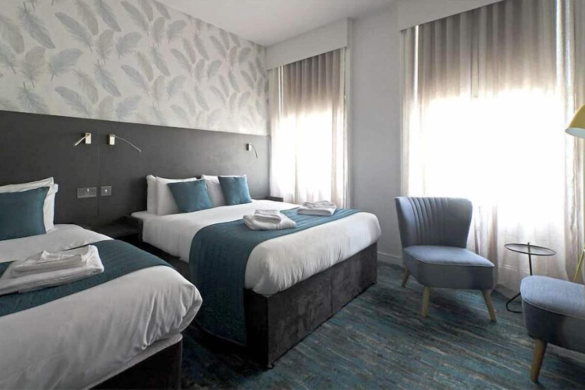 A hotel room with two beds, a chair, and a small table.