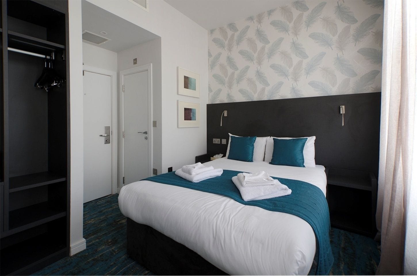Une chambre d’hôtel avec un grand lit, une armoire et une porte donnant sur une autre pièce.