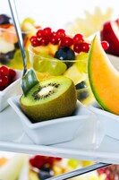 Una ciotola di frutta con kiwi, melone e frutti di bosco.