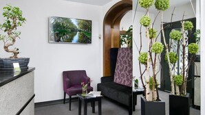 A reception area with a reception desk, purple seating, a large mirror, and a framed painting on the wall.
