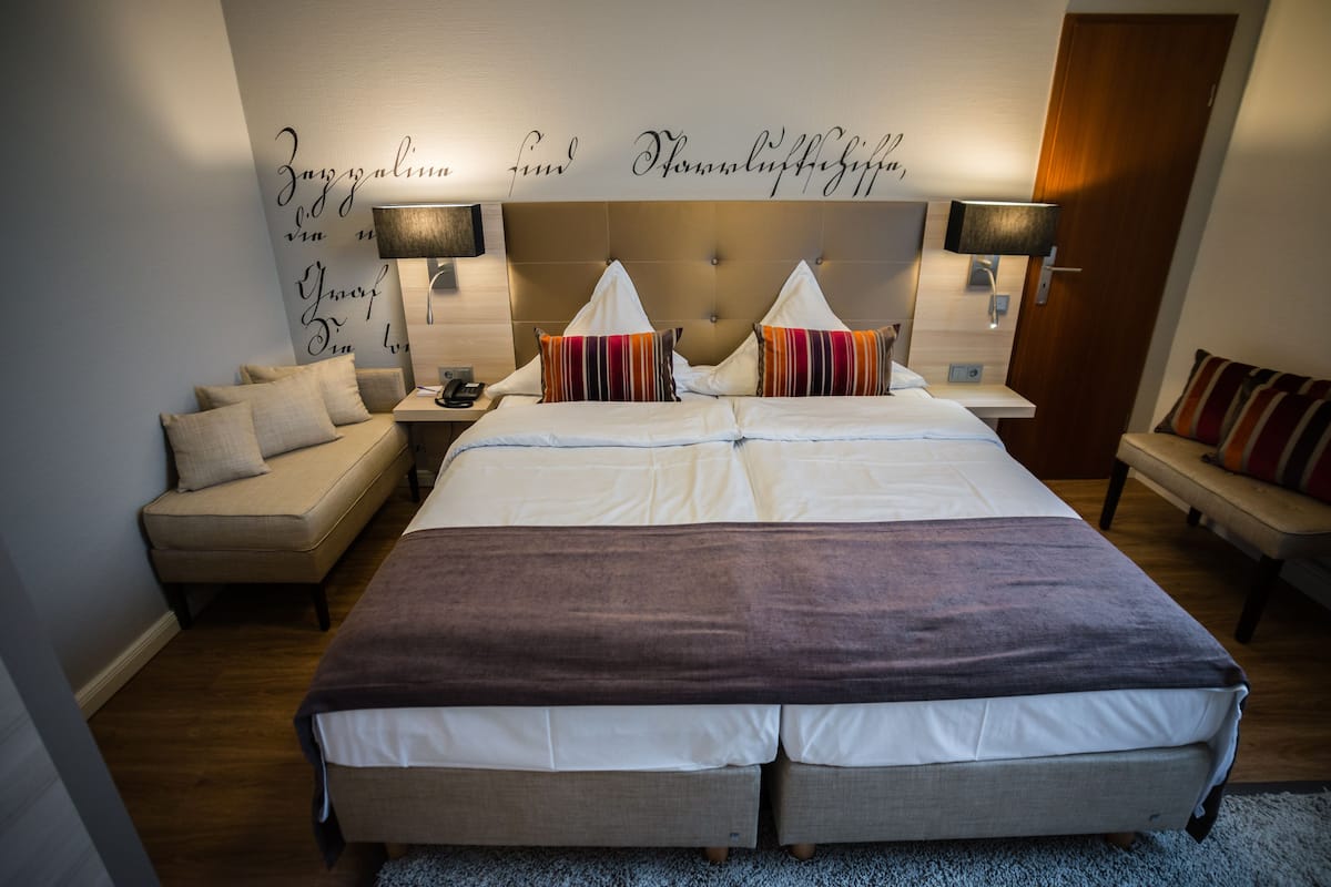 A double bed with a headboard, two bedside tables, a nightstand, and a sofa.