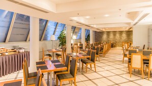 Un vaste espace dédié à la salle à manger, doté de hauts plafonds, de grandes fenêtres et d’un design moderne.