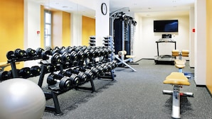 Une salle de sport équipée de divers appareils d’exercice, notamment des haltères, un banc et un appareil de rameur.