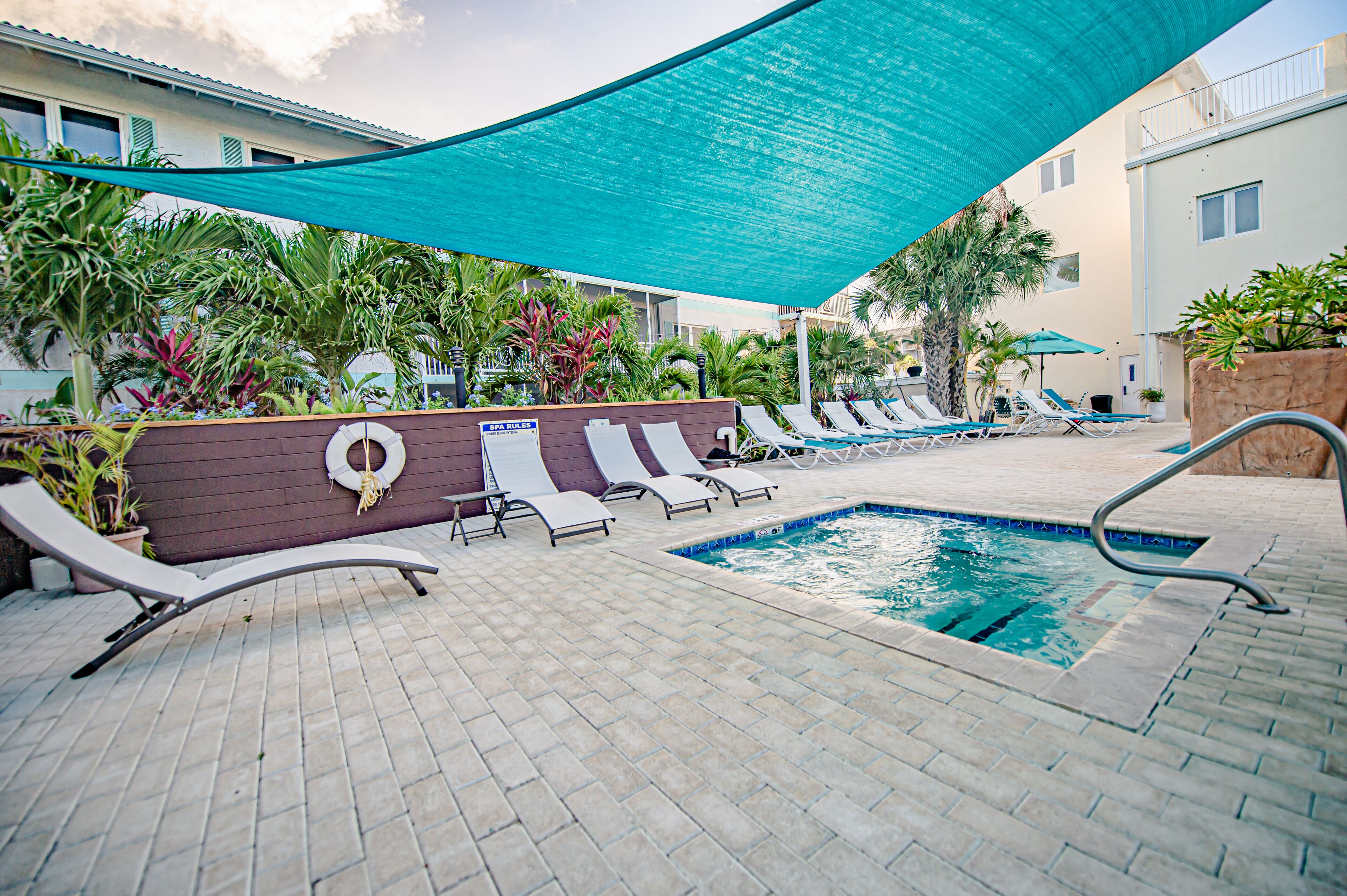 A pool area with lounge chairs, a pool, and a shaded canopy.