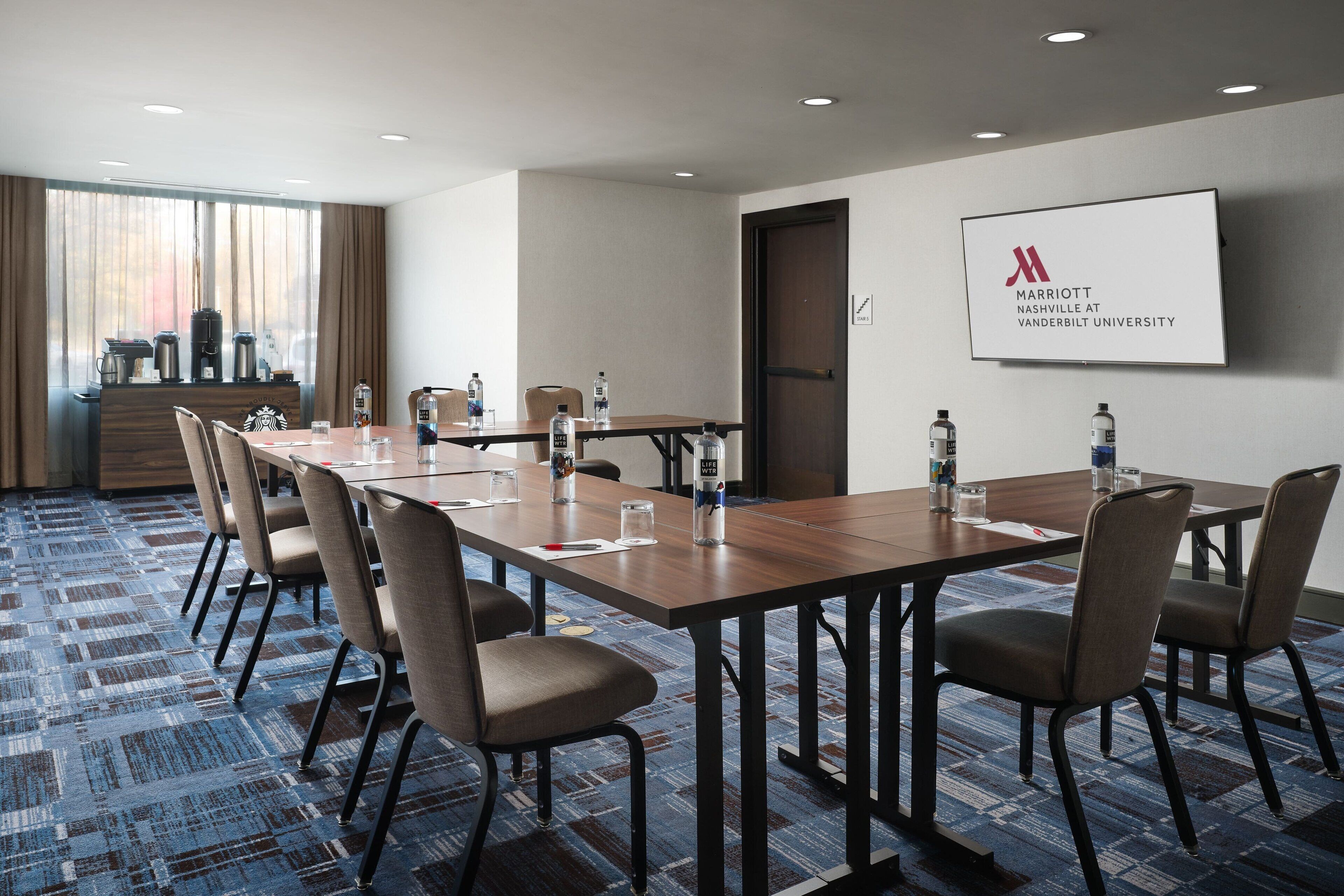 A conference room with a long table, chairs, and a screen displaying the Marriott Nashville at Vanderbilt University logo.