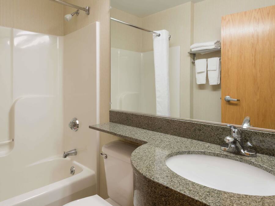 A bathroom with a bathtub, a sink, a mirror, and a towel rack.