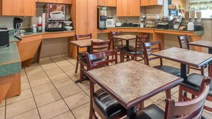 Une cuisine dotée de meubles en bois, d’une machine à café, d’un four à micro-ondes et d’un espace dédié à la préparation du café. On y trouve également des tables et des chaises pour prendre les repas.