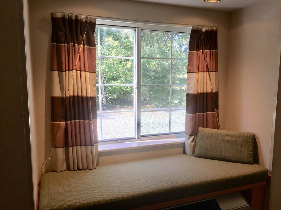 Una habitación con ventana, un banco y cortinas.
