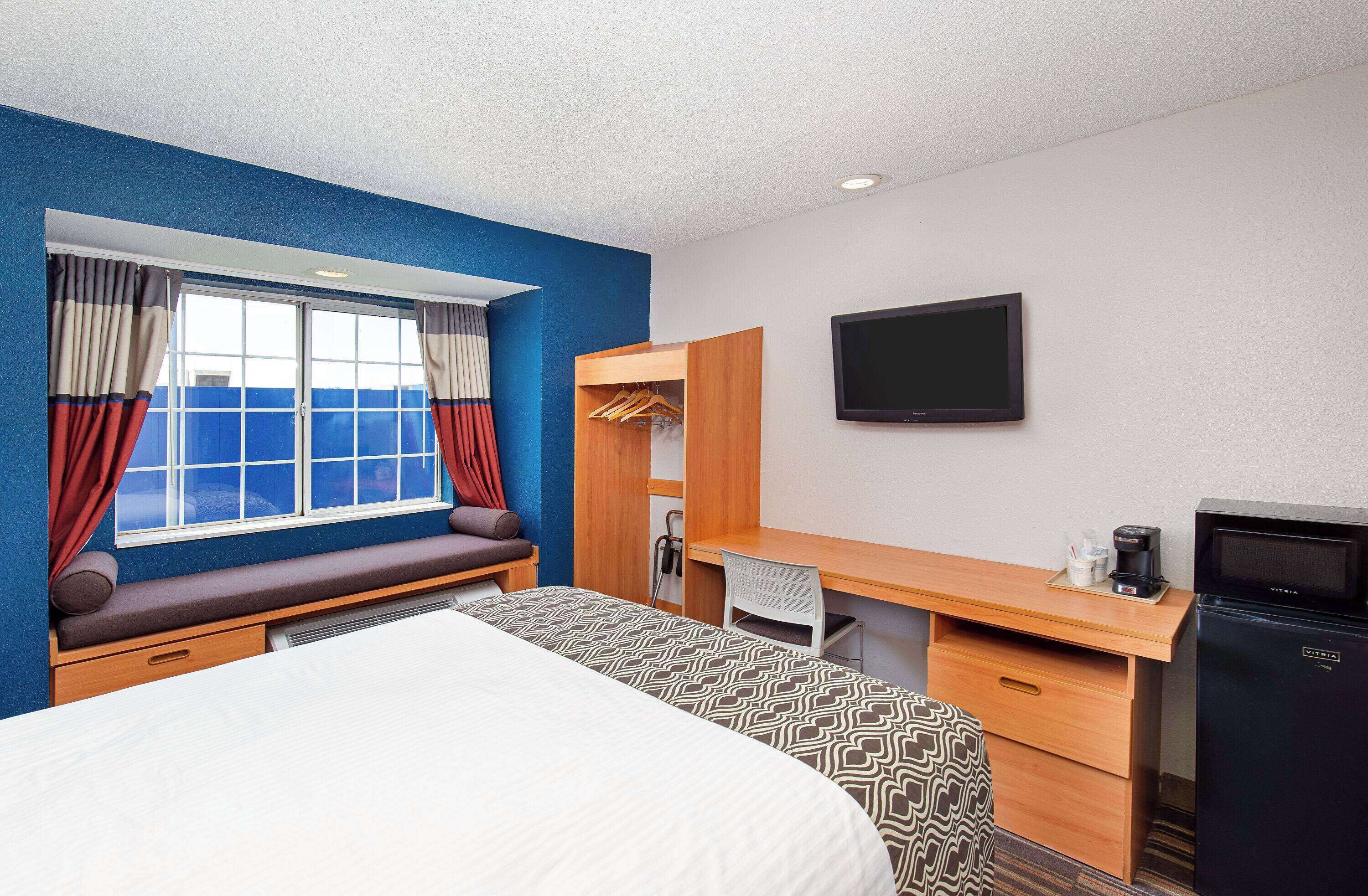 A hotel room with a bed, a desk, a TV, and a wardrobe.